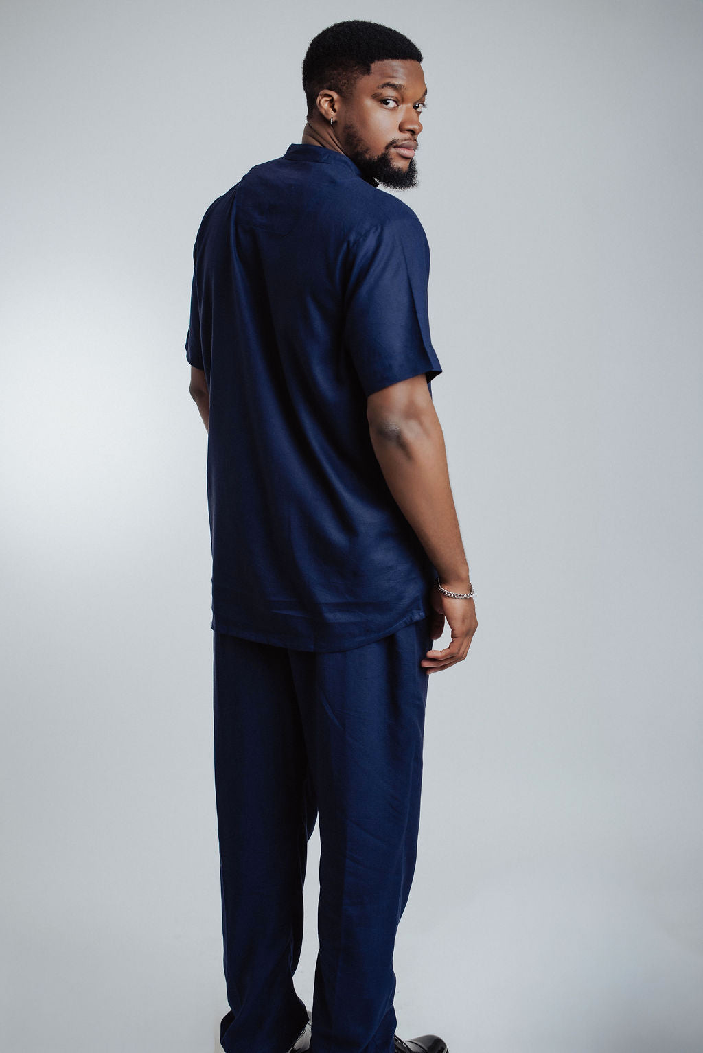 Man wearing a navy blue outfit against a plain background