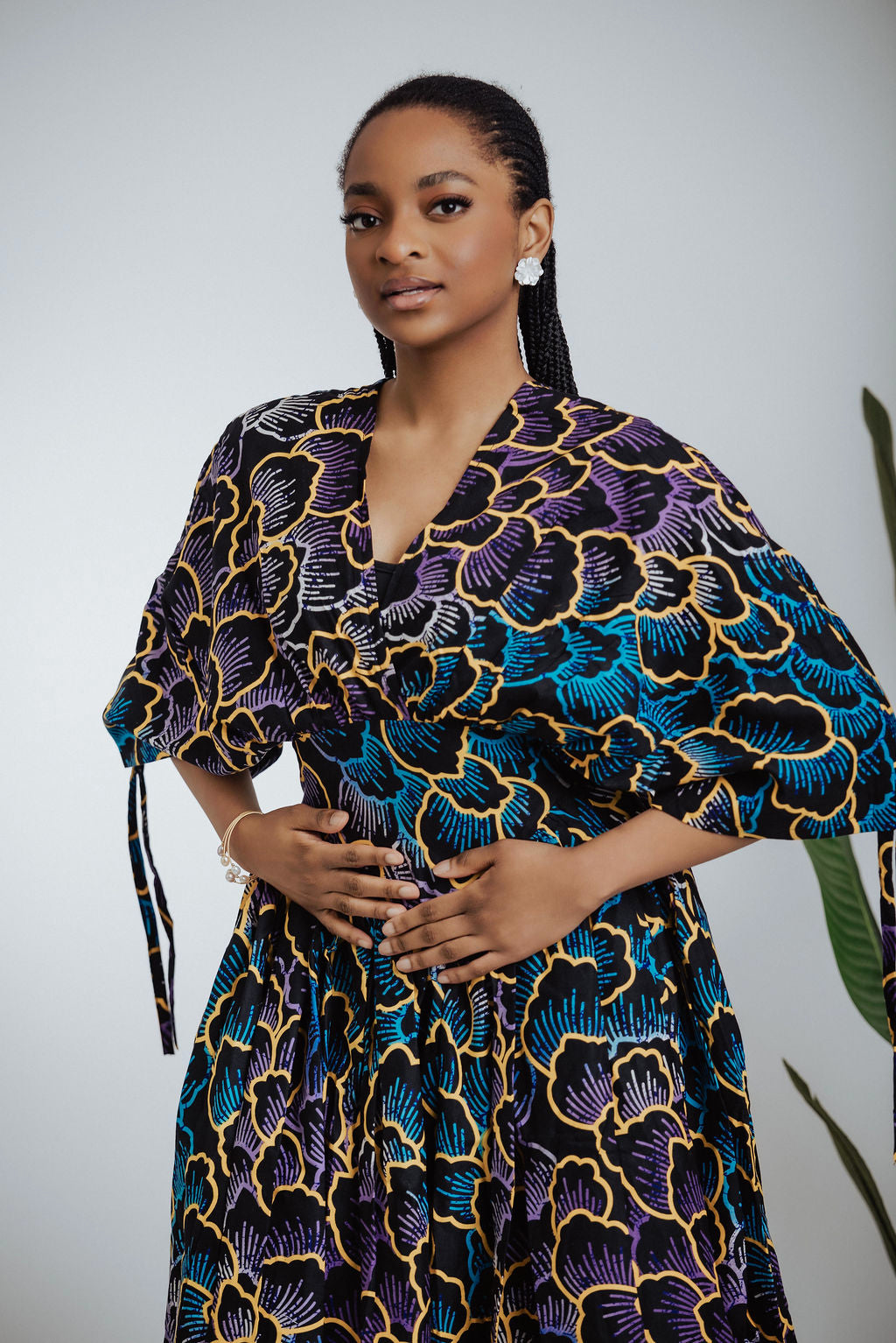 Woman wearing a colorful African print patterned outfit against a plain background