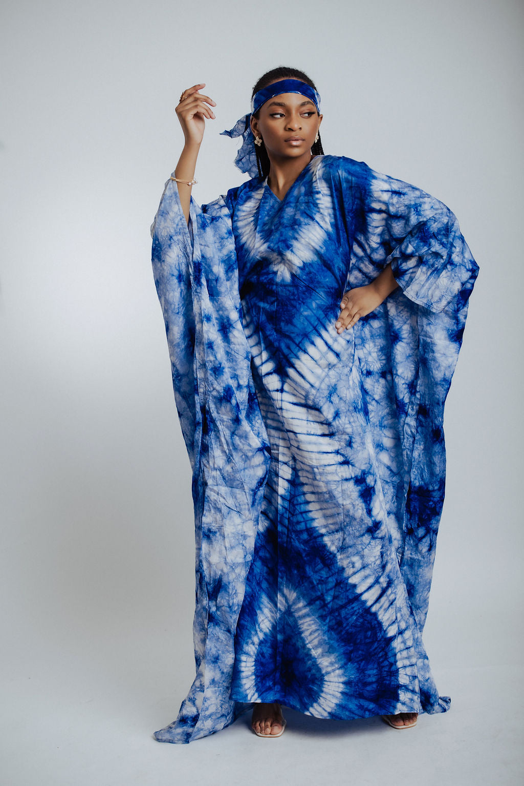 Woman wearing a blue tie-dye dress against a white background