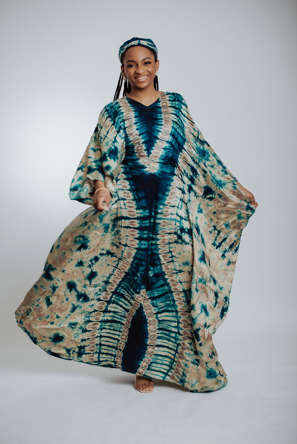 Woman wearing a green & cream tie-dye dress on a white background