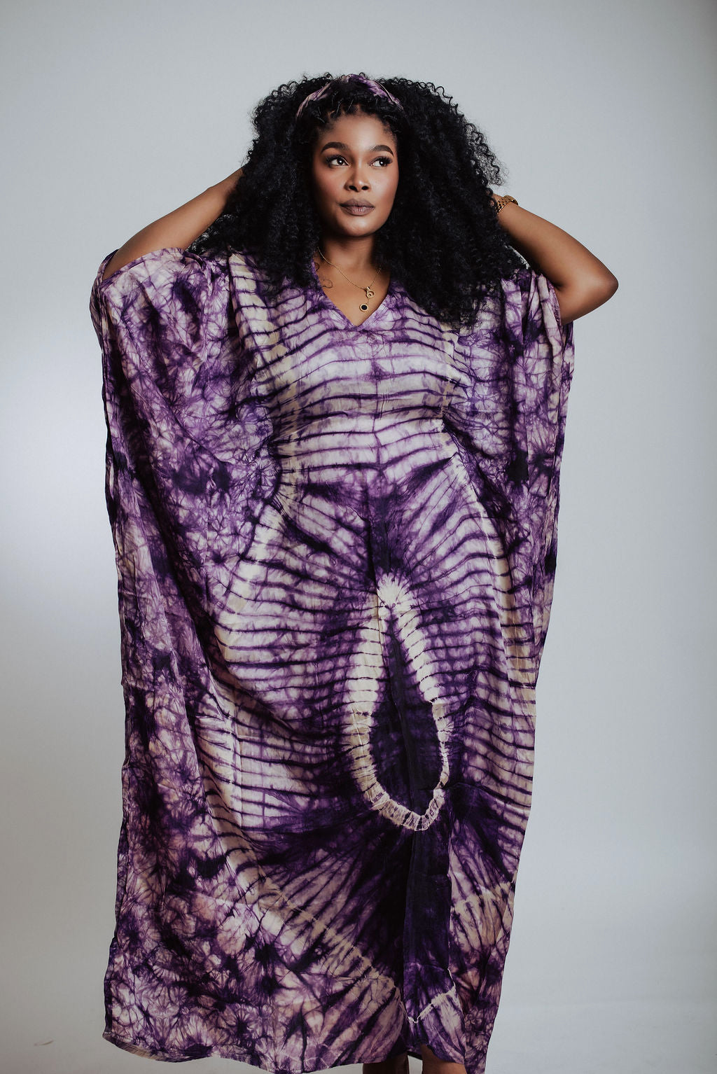 Woman wearing a purple tie-dye dress with a plain background