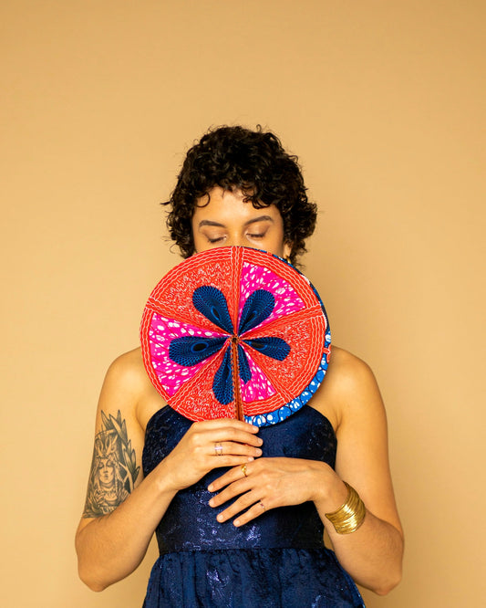 Woman holding colorful african fan in front of face