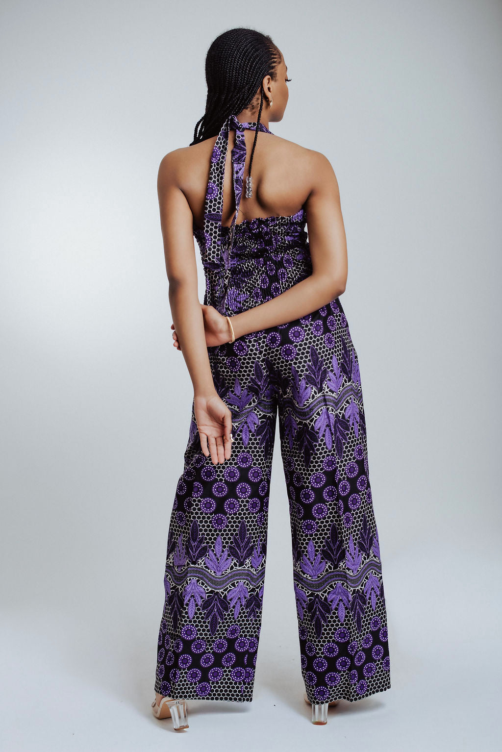 Back view of woman wearing a purple patterned 2 piece set on a white background