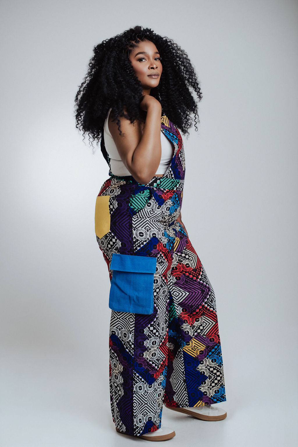 Woman wearing a colorful patterned jumpsuit on a white background