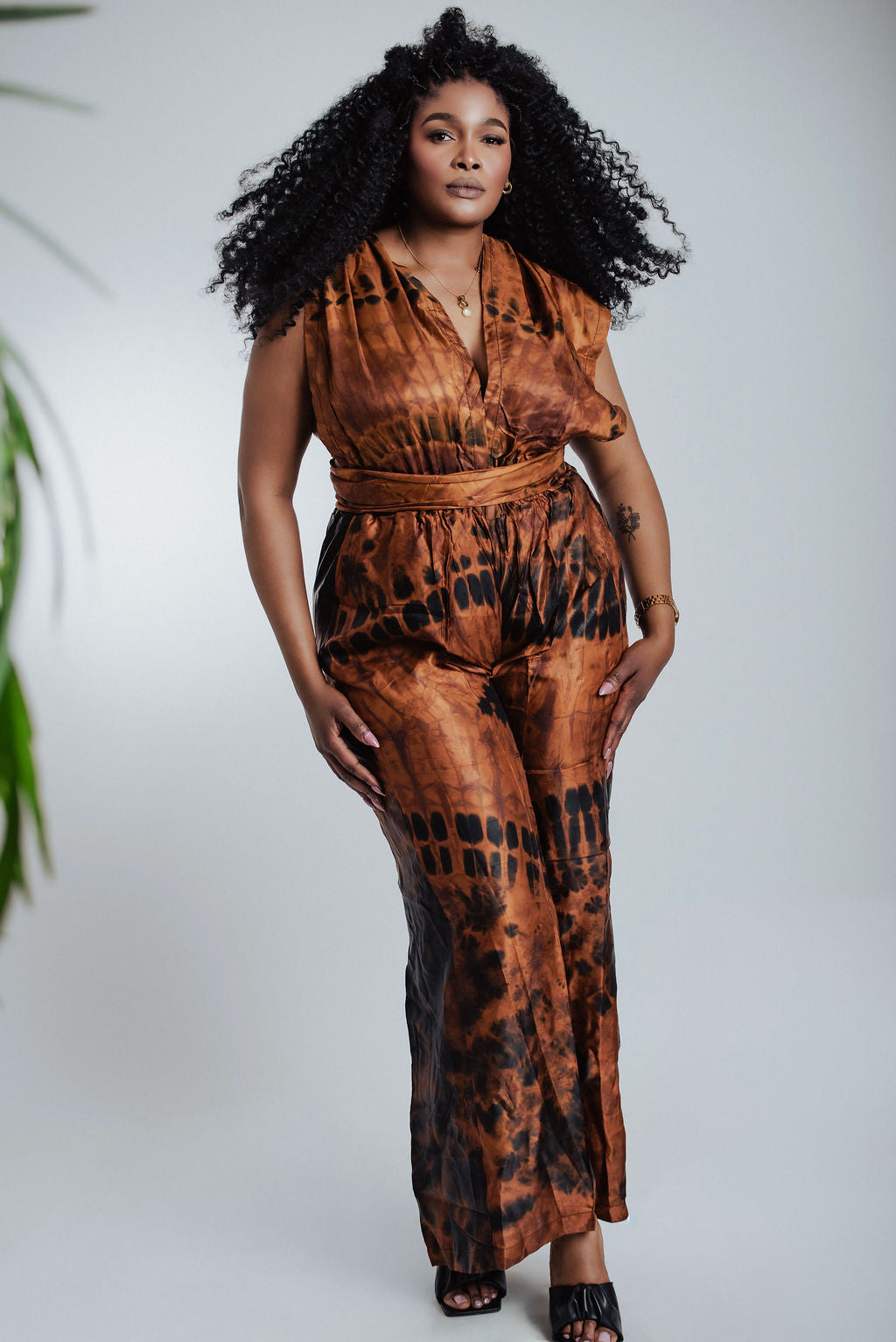 Woman wearing a brown patterned jumpsuit against a white background