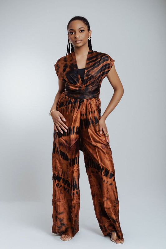 Woman wearing a brown and black tie-dye jumpsuit on a white background
