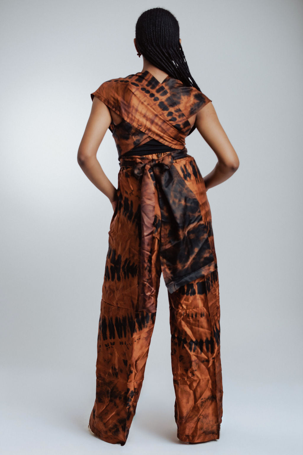 Person wearing a brown and black patterned jumpsuit on a white background