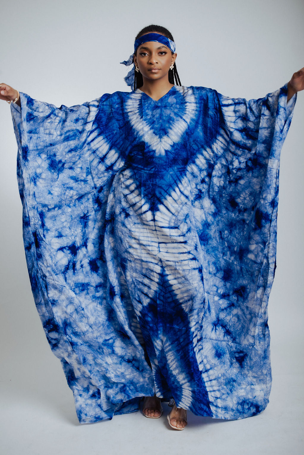 Woman wearing a blue and white tie-dye dress on a plain background