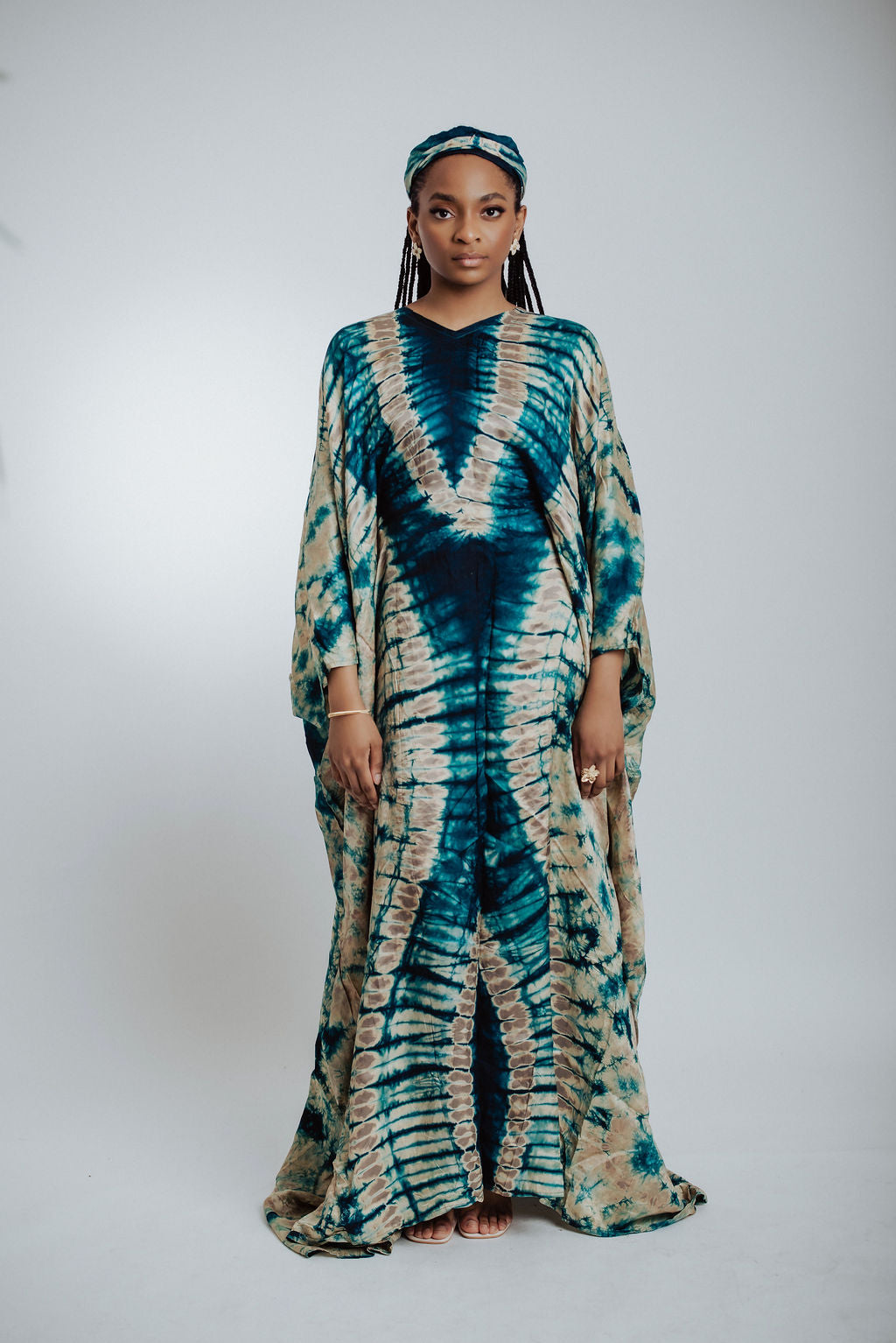 Woman wearing a green & cream tie-dye dress on a white background