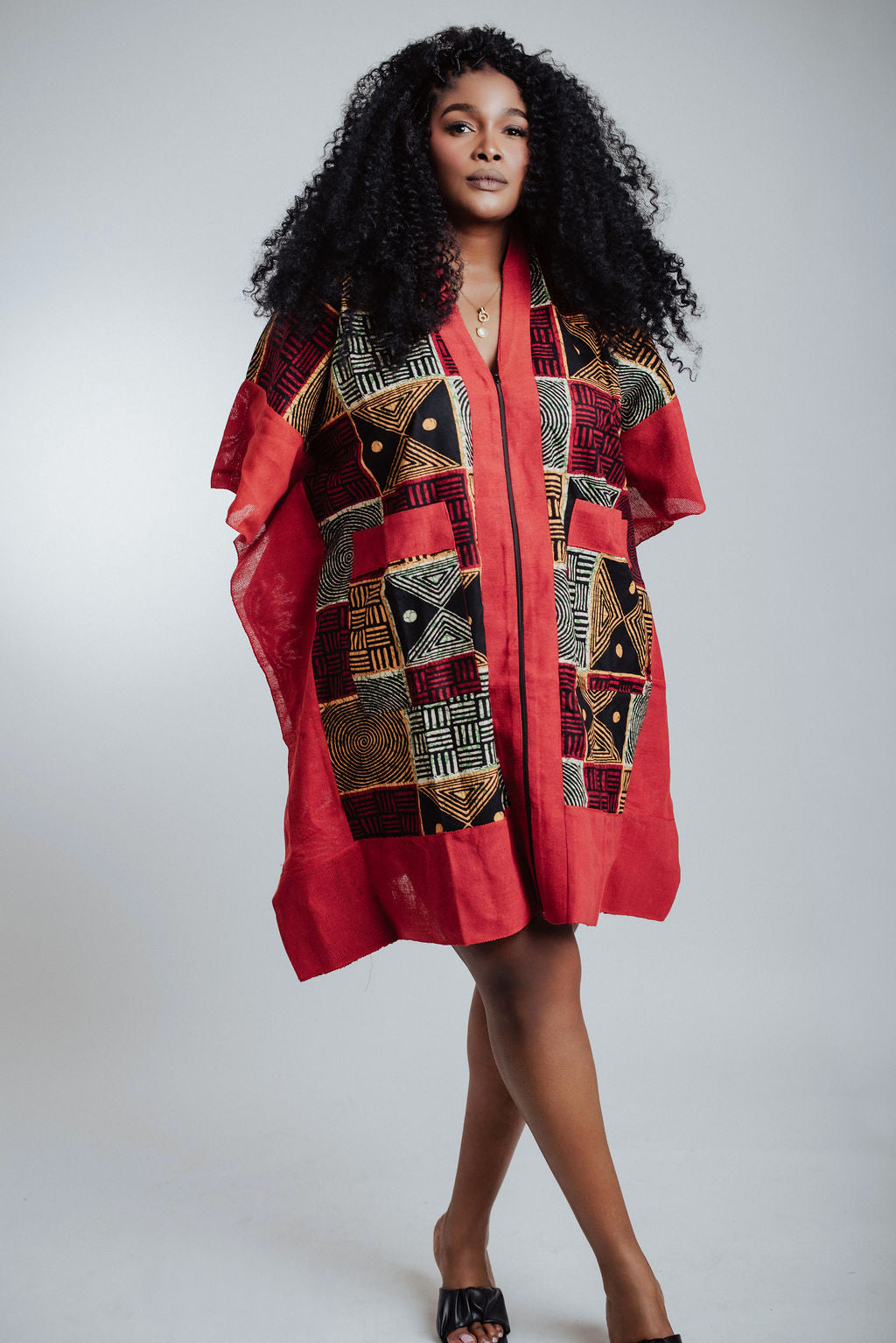 Woman wearing a red dress with black & yellow patterns  against a white background