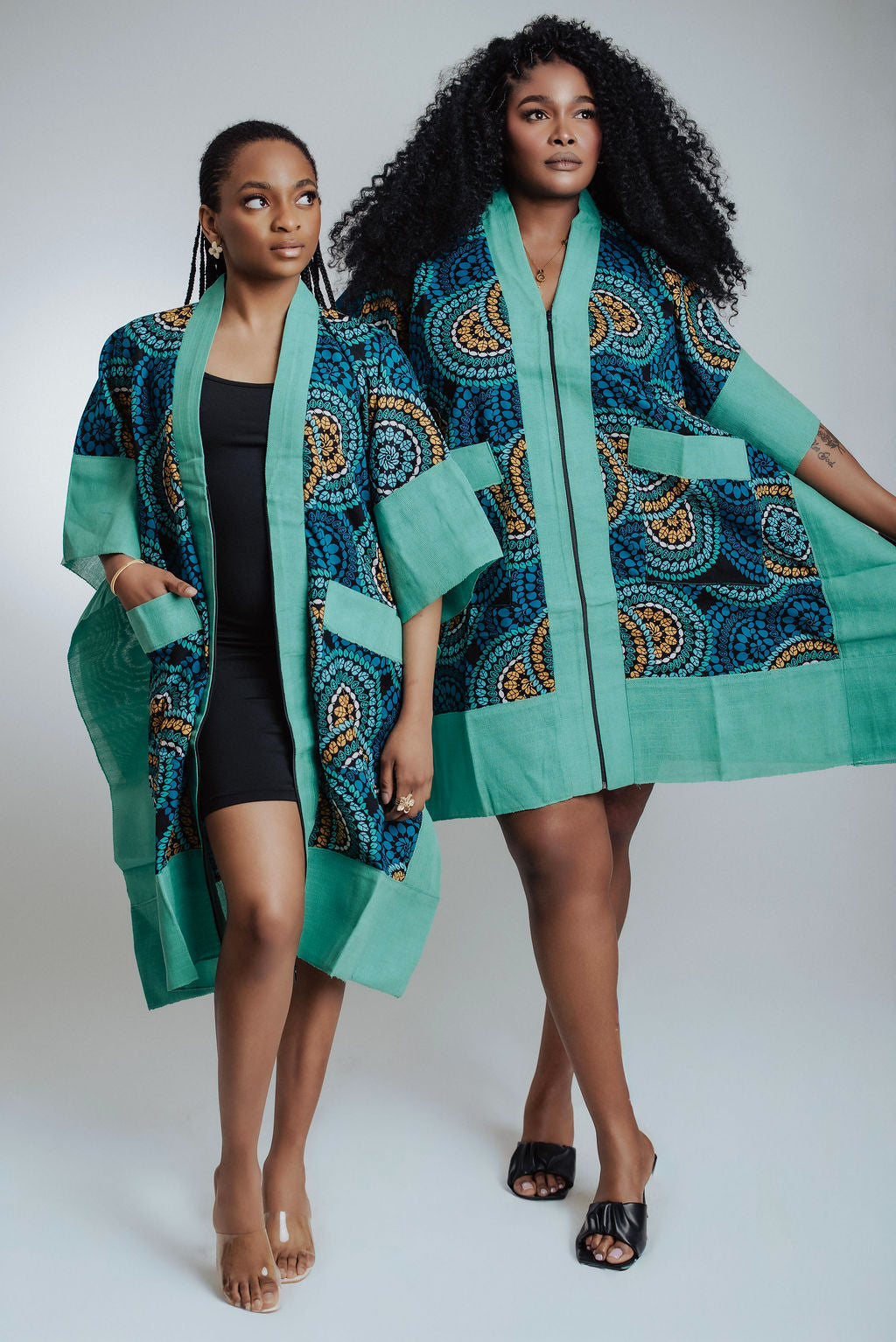 Two models wearing teal and black patterned outfits on a white background