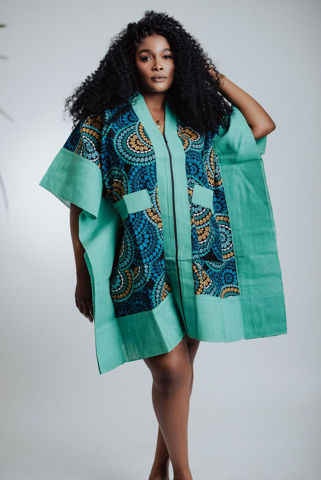 Woman wearing a teal and patterned kimono-style dress against a white background