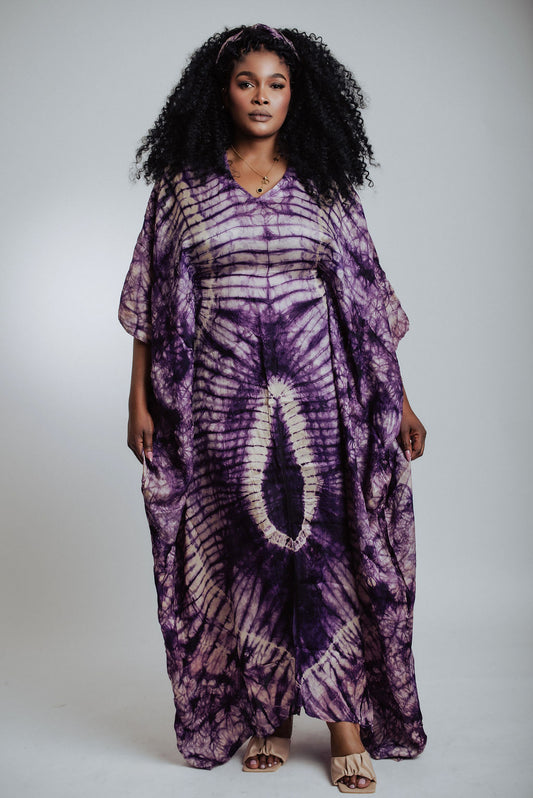 Woman wearing a purple tie-dye dress against a plain background