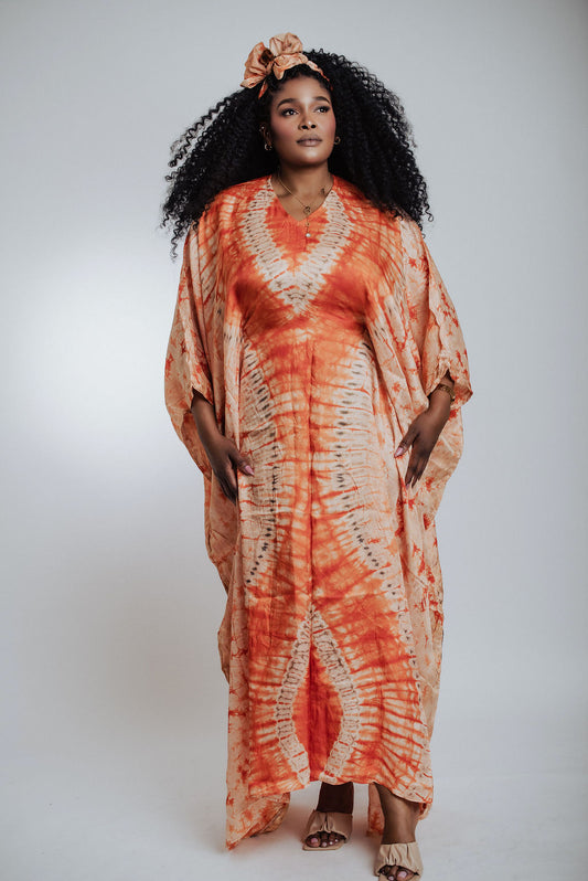 Woman wearing an orange tie-dye dress with a plain background